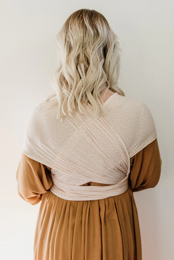 Back view of a blonde woman with the shoulder passes of a pearl stretch wrap spread across her back