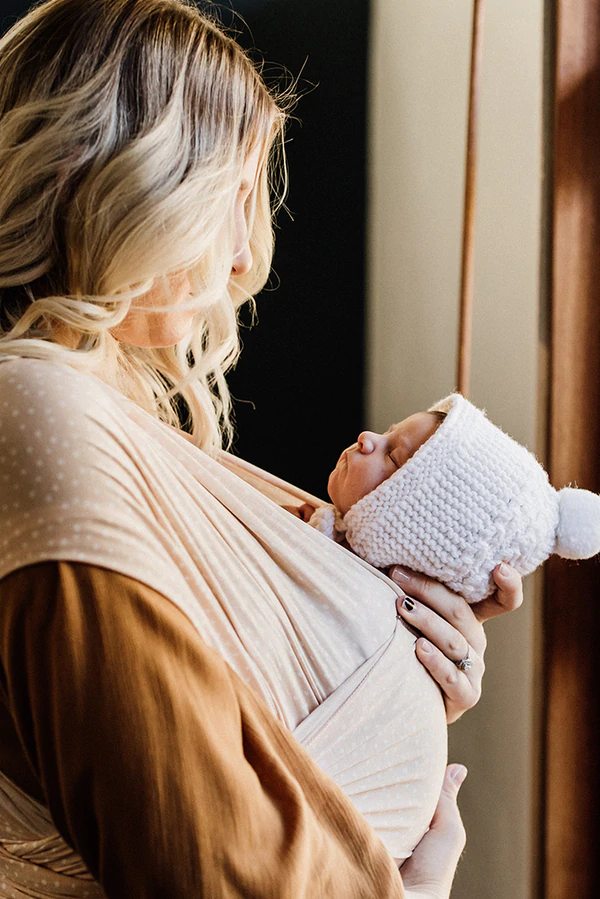 Blonde mother carrying newborn in a pearl vixsa stretch wrap viewed from the side