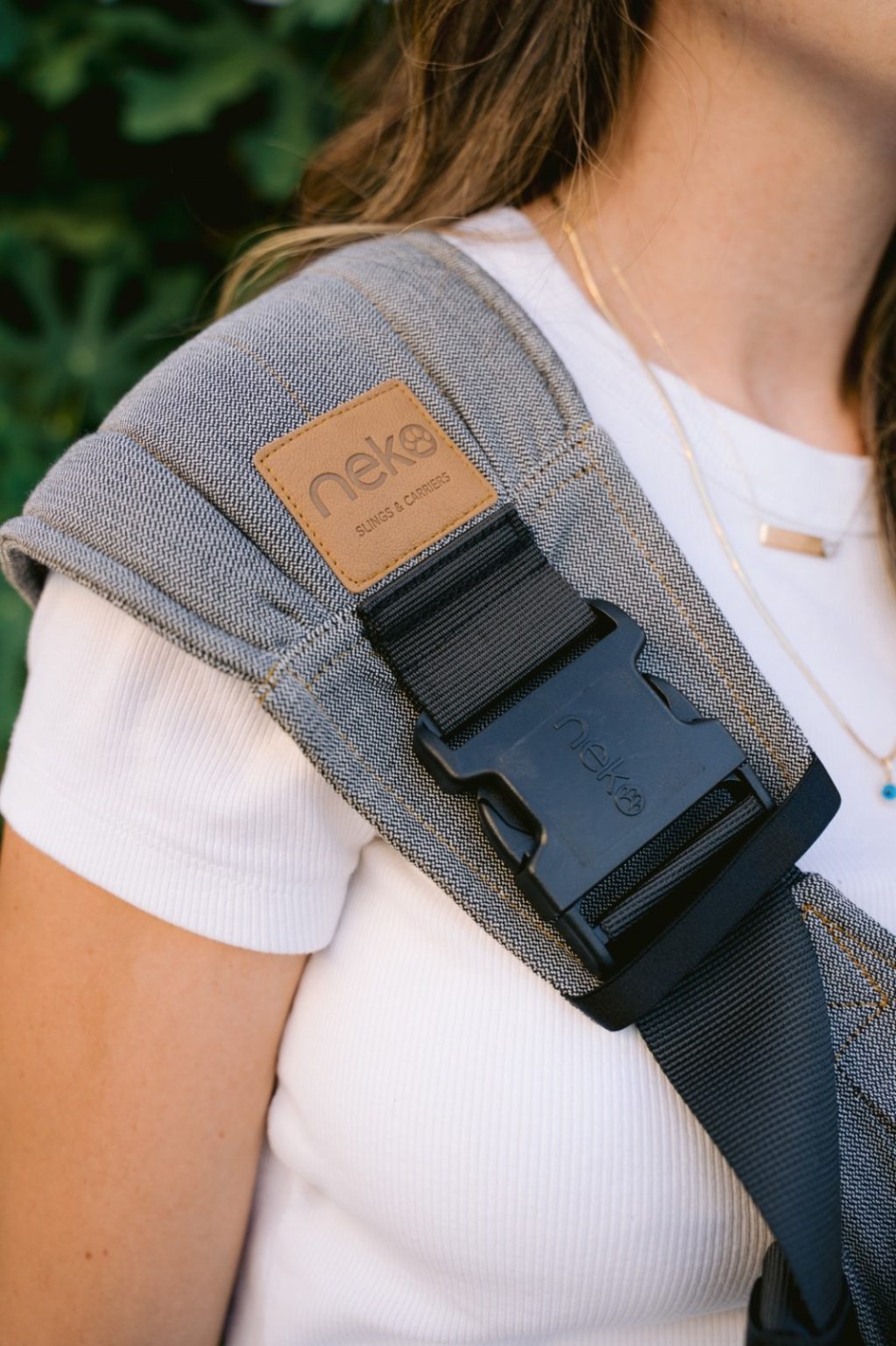 Grey shoulder strap for carry assist sling with black buckle and webbing worn by person in white t-shirt
